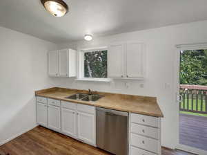 Kitchen featuring dishwasher, dark wood-style flooring, white cabinets, and light countertops