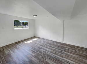 Spare room featuring dark wood-type flooring and baseboards