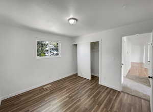 Unfurnished bedroom featuring dark wood finished floors and a closet