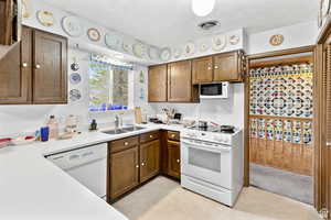 Kitchen featuring white appliances, light countertops, brown cabinets, and light tile patterned floors
