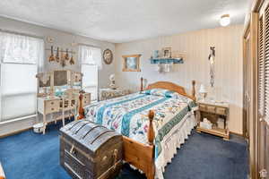 Carpeted bedroom with a textured ceiling and wallpapered walls
