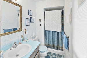 Full bathroom with vanity, a shower stall, and wallpapered walls
