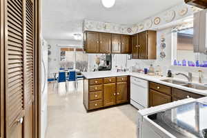 Kitchen featuring white appliances, light countertops, a peninsula, and light flooring