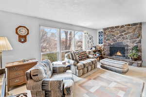 Carpeted living area with a stone fireplace and a textured ceiling