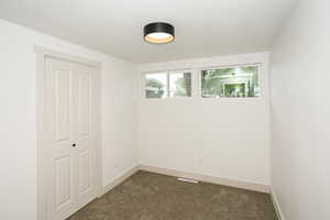 Unfurnished room featuring dark colored carpet and a textured ceiling