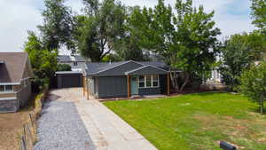 View of front of property featuring concrete driveway, board and batten siding, a garage, a front lawn, and roof with shingles