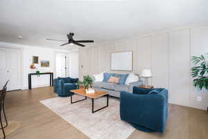 Living area featuring a decorative wall, wood finished floors, and ceiling fan