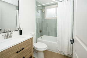 Full bath featuring shower / bath combo with shower curtain, vanity, and light wood finished floors
