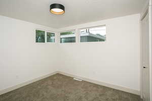 Carpeted empty room with baseboards and a textured ceiling