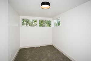 Spare room with dark colored carpet and baseboards