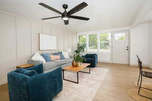 Living room with a decorative wall, light wood-style flooring, and ceiling fan