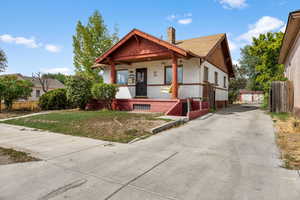 Bungalow-style house with a porch, a chimney, driveway, brick siding, and an outdoor structure