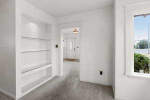 Corridor with light carpet and built in shelves