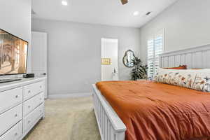 Bedroom featuring light carpet, recessed lighting, ceiling fan, and ensuite bath