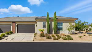 View of front of house featuring stucco siding, driveway, a tile roof, and an attached garage