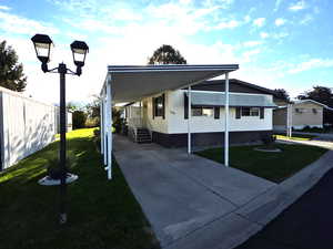 1680 sq ft mobile home with a front lawn, two carports, and concrete driveway
