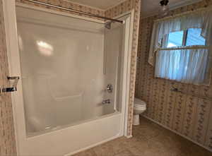 Full master bath with wallpapered walls,  shower combination, and tile patterned floors
