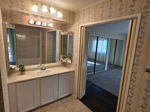 Master Bathroom featuring vanity, wallpapered walls, light tile patterned floors, and ornamental molding