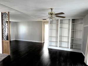 Unfurnished living room featuring dark wood-style floors, a ceiling fan, and built in features