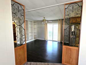 Unfurnished living room featuring dark wood-style flooring, a ceiling fan, and built in shelves