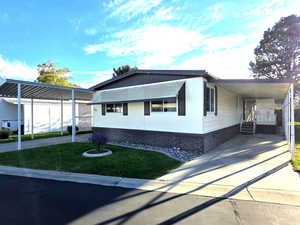 View of side of property with a carport, driveway, and a yard