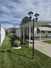 Back of house with a lawn, a mountain view, an attached carport, and concrete driveway