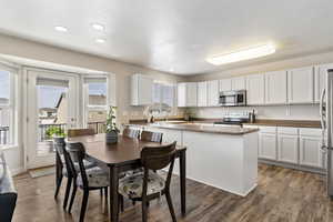 Kitchen featuring white cabinets, light wood-type flooring, stainless steel appliances, recessed lighting, and dark stone counters