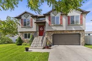 Split foyer home featuring stone siding, stucco siding, driveway, and a garage