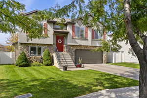 View of front of property featuring stone siding, stucco siding, concrete driveway, and a garage