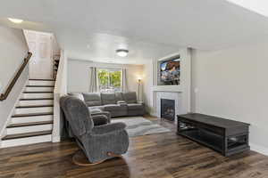 Living area with stairway, a fireplace, dark wood finished floors, and a textured ceiling