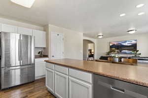 Kitchen with appliances with stainless steel finishes, arched walkways, dark wood-style floors, white cabinets, and open floor plan