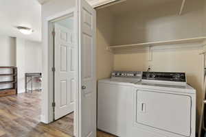 Washroom with light wood-style flooring and washer and clothes dryer