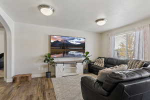 Living room featuring arched walkways, wood finished floors, and a textured ceiling