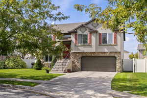 View of front facade featuring stone siding, a gate, concrete driveway, an attached garage, and stucco siding