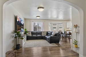 Living room with arched walkways and wood finished floors