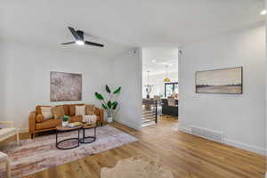 Living room featuring ornamental molding, light wood-type flooring, ceiling fan, and recessed lighting