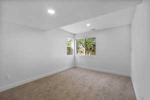 Carpeted empty room featuring a textured ceiling and recessed lighting