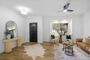 Foyer with ornamental molding, wood finished floors, and ceiling fan