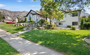 View of front of house with a front lawn, a mountain view, and brick siding