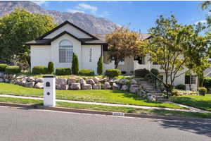 Ranch-style home featuring a front lawn, a mountain view, stairway, brick siding, and roof with shingles