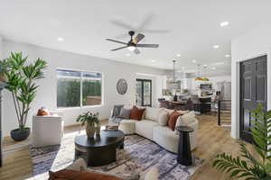 Living room featuring light wood-style flooring, recessed lighting, a chandelier, and a ceiling fan