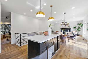 Kitchen with plenty of natural light, recessed lighting, decorative light fixtures, a glass covered fireplace, and a center island