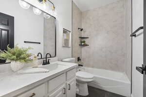 Full bathroom with shower / bathtub combination, vanity, and dark tile patterned floors