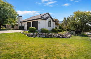 View of side of property with a lawn, concrete driveway, a garage, and a chimney