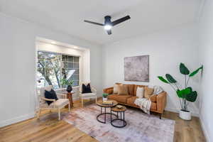 Living area featuring ornamental molding, light wood-type flooring, and a ceiling fan