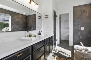 Full bathroom featuring a tile shower, vanity, and light tile patterned flooring