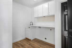 Washroom with cabinet space, light wood finished floors, and electric dryer hookup
