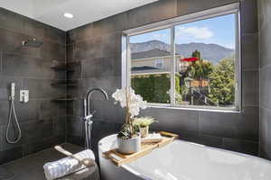 Full bath featuring a mountain view, a soaking tub, tile walls, a tile shower, and recessed lighting