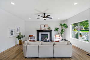 Living area featuring recessed lighting, a fireplace, light wood-style flooring, and a ceiling fan