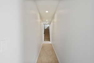 Hall with recessed lighting, light colored carpet, and stairway